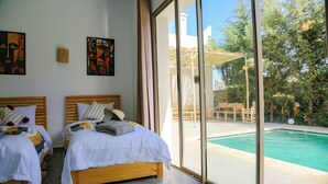 A bedroom with two beds, a large window, and a view of an outdoor swimming pool.