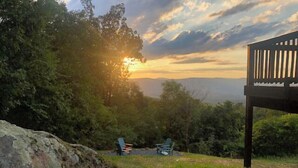 A serene outdoor seating area with a view of the sunset over a mountainous landscape. - Spectacular Mountain Views. Peaceful Solitude. Rustic cabin with modern comforts. 90 mins from DC (Rileyville)