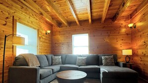 A cozy log cabin interior with a sectional sofa, a round coffee table, and two floor lamps. - Million Dollar Views. Peaceful Solitude. Rustic cabin.  90 minutes from DC. (Rileyville)