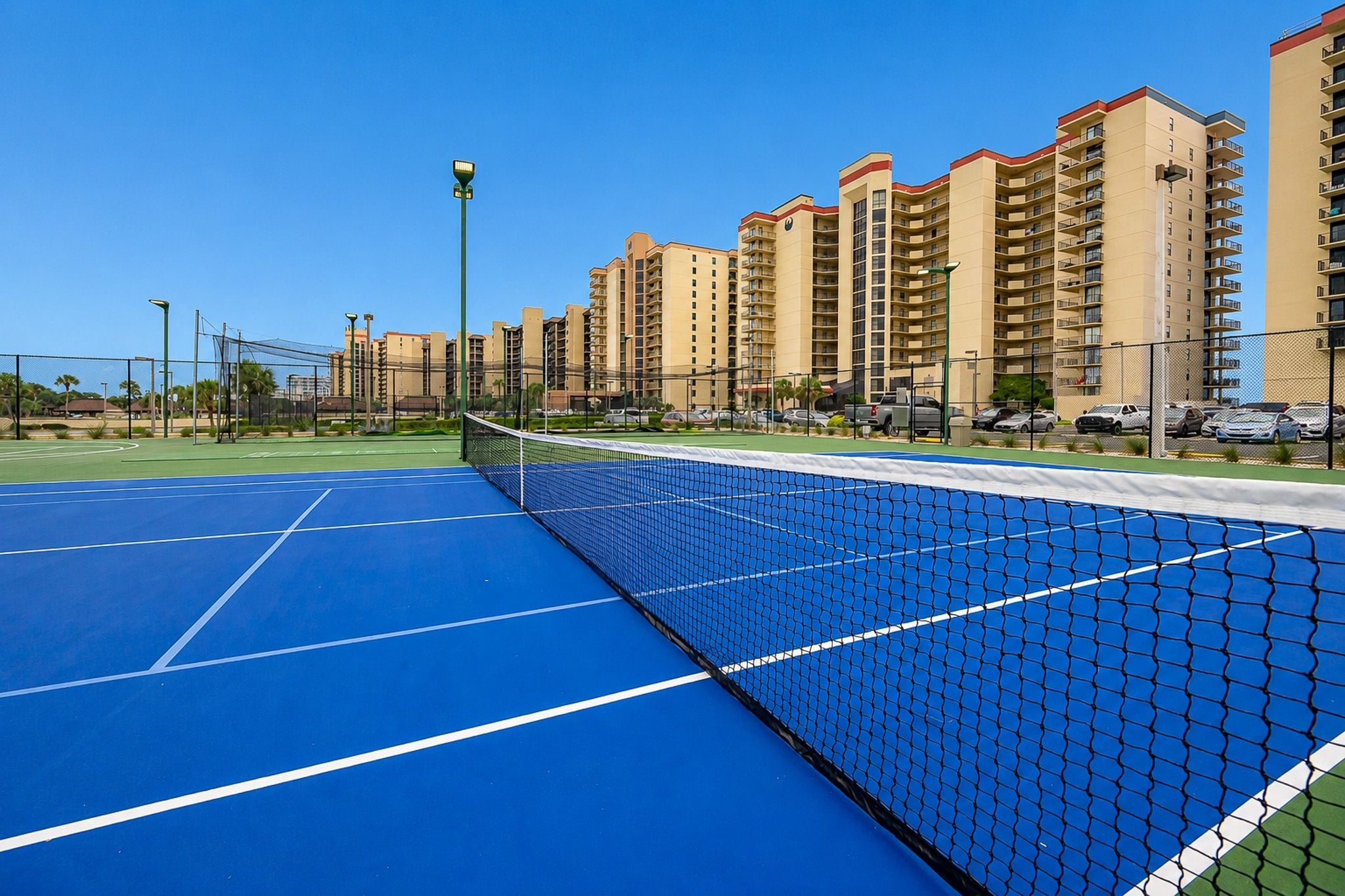 Una cancha de tenis con una red, rodeada de edificios altos.