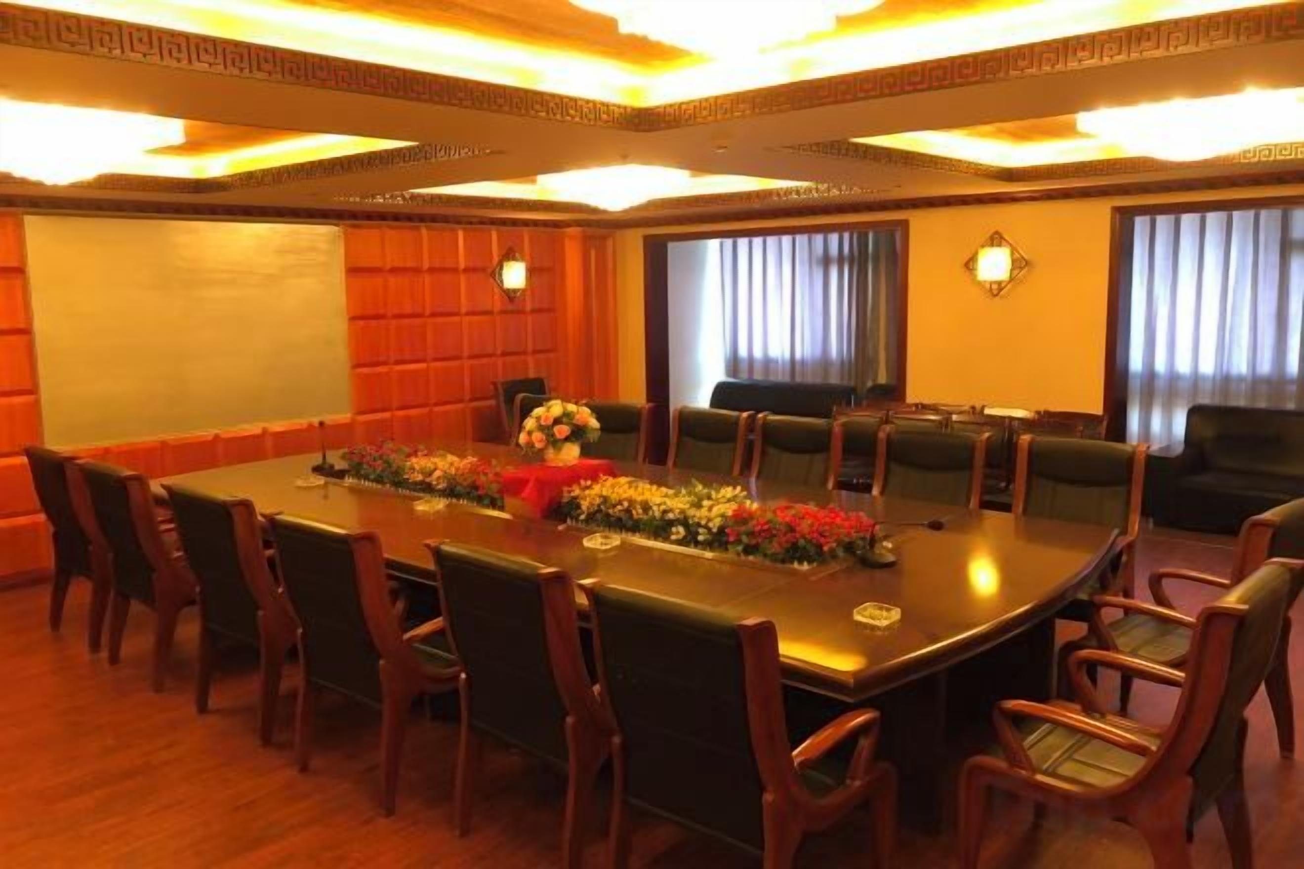 A conference room with a long table, multiple chairs, and a projector screen.