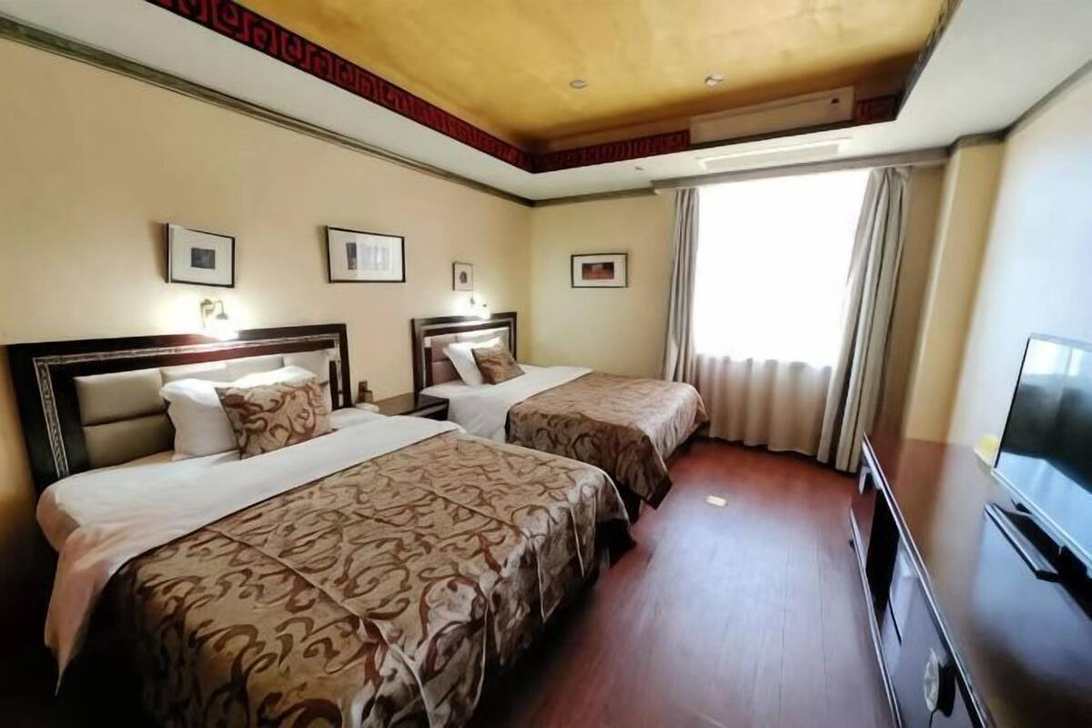 Een hotelkamer met twee bedden, een televisie en een raam met gordijnen.