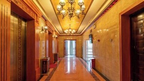 A hotel hallway with a marble floor, a red carpet, a chandelier, and a large door on the right. - Yijia Hotel (Wuding)