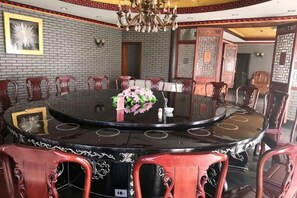 Une table de salle à manger ronde, avec des chaises, un lustre et un arrangement floral en guise de centre de table.