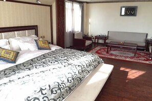 Une chambre d’hôtel avec un grand lit, un canapé, une petite table et une fenêtre avec des rideaux.