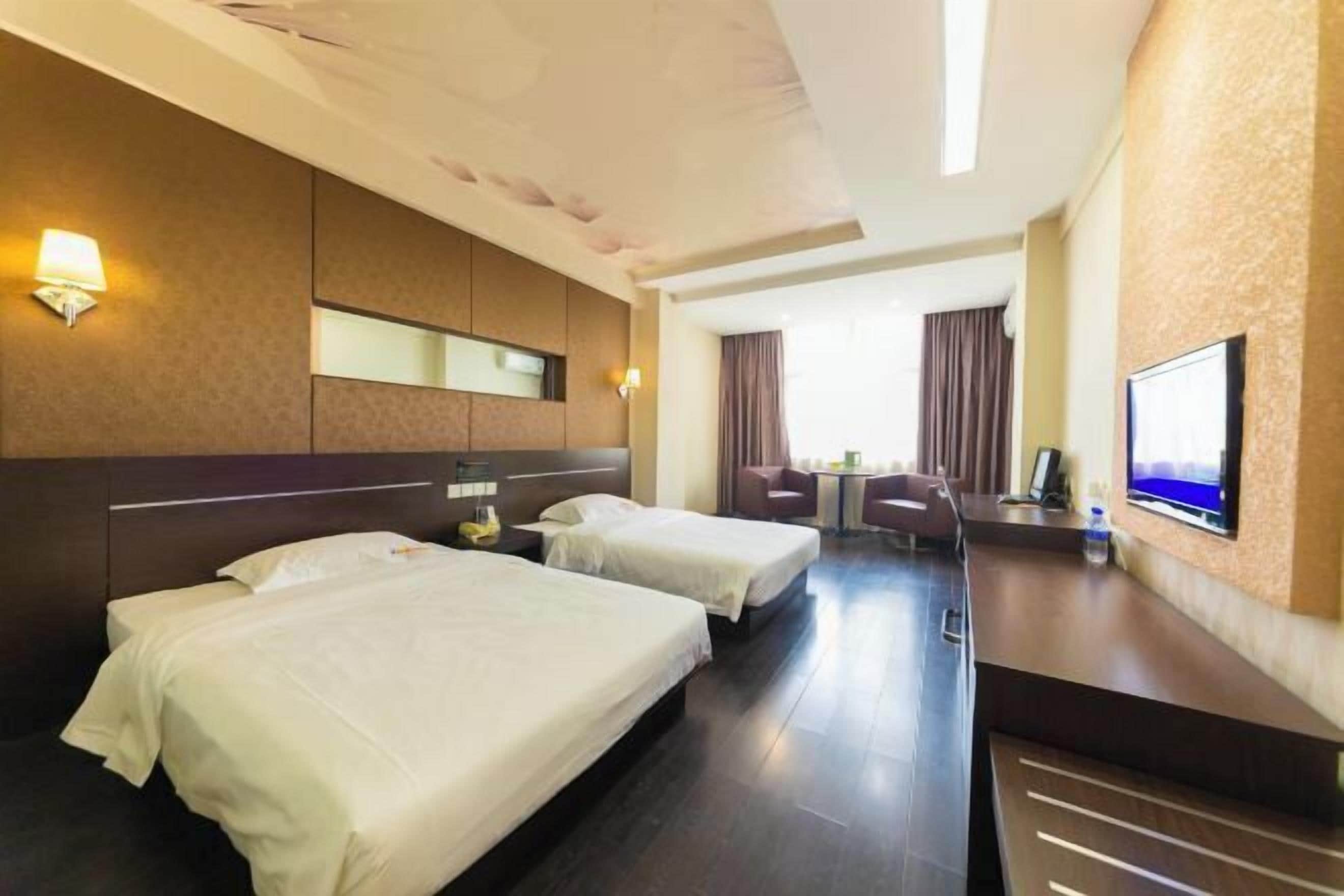 A hotel room with two beds, a desk, a chair, a TV, and a window with curtains.