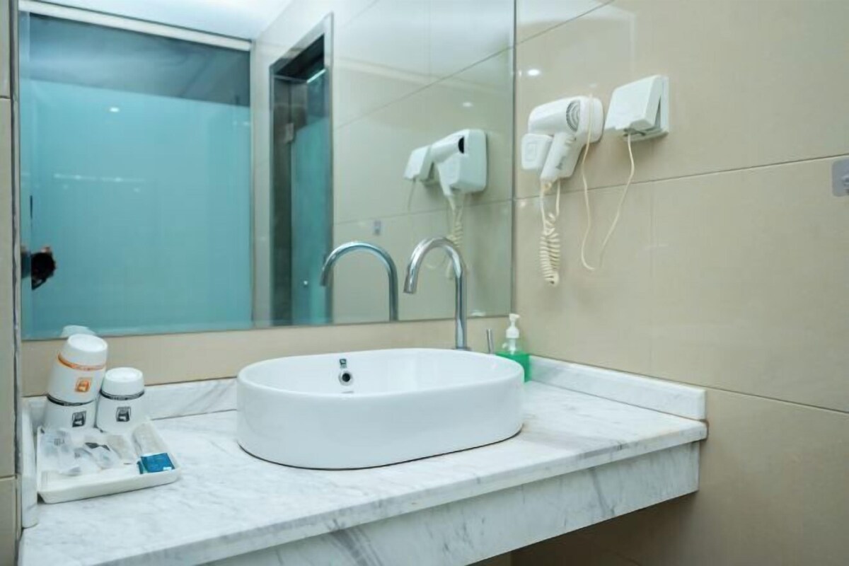 A modern bathroom with a white sink, a mirror, a hairdryer, and a telephone.