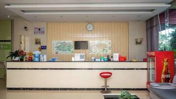 A reception area with a counter, a clock, and a television.