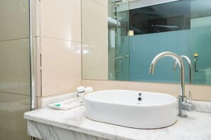 A modern bathroom with a white sink, a glass shower enclosure, and a marble countertop. - Mangshi Beautiful Spring Business Hotel (Mangshi)