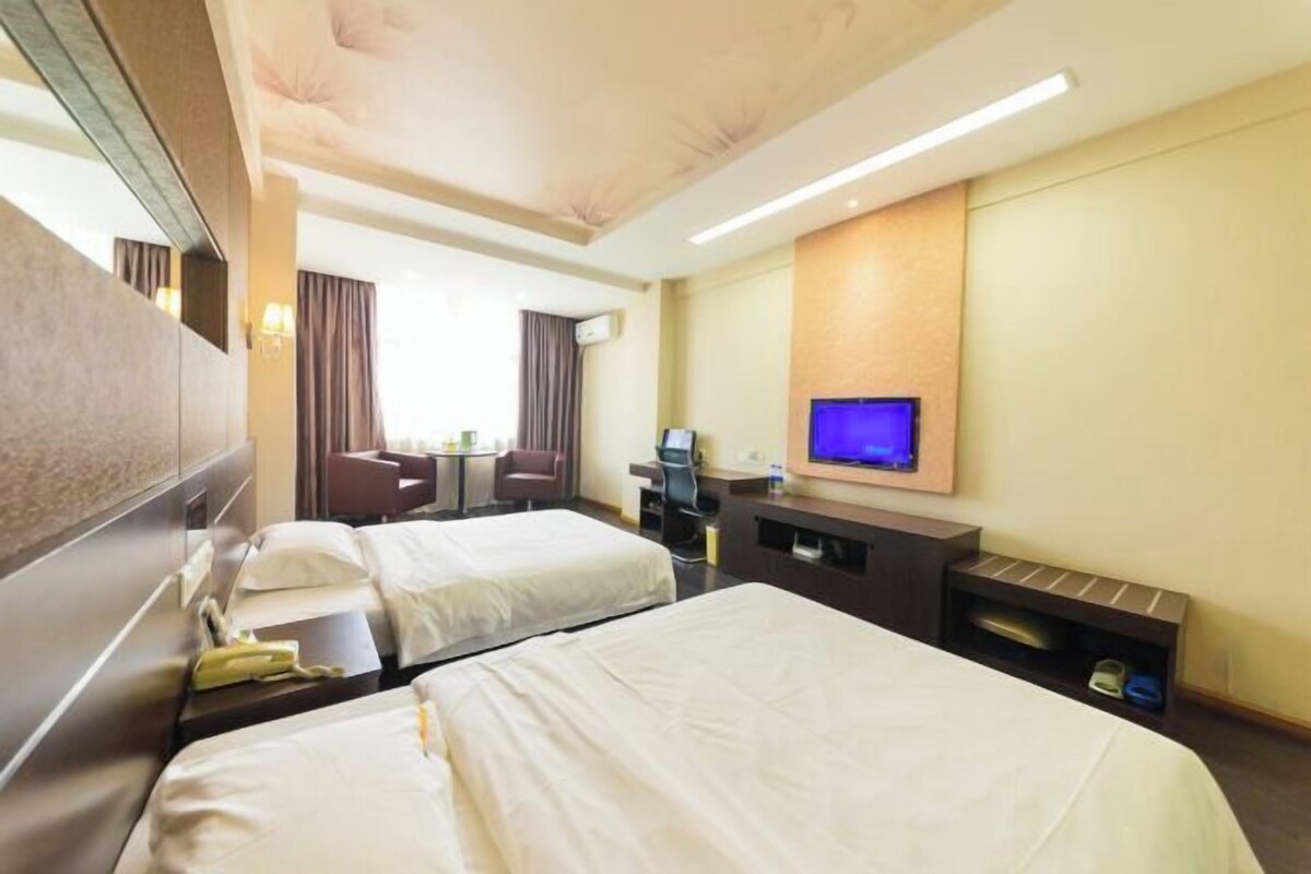 A hotel room with two beds, a desk, a chair, a television, and a small shelf with shoes.