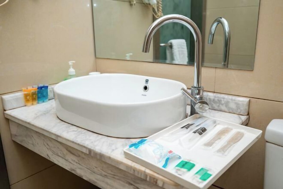 A bathroom with a white sink, a mirror, and toiletries on the counter.