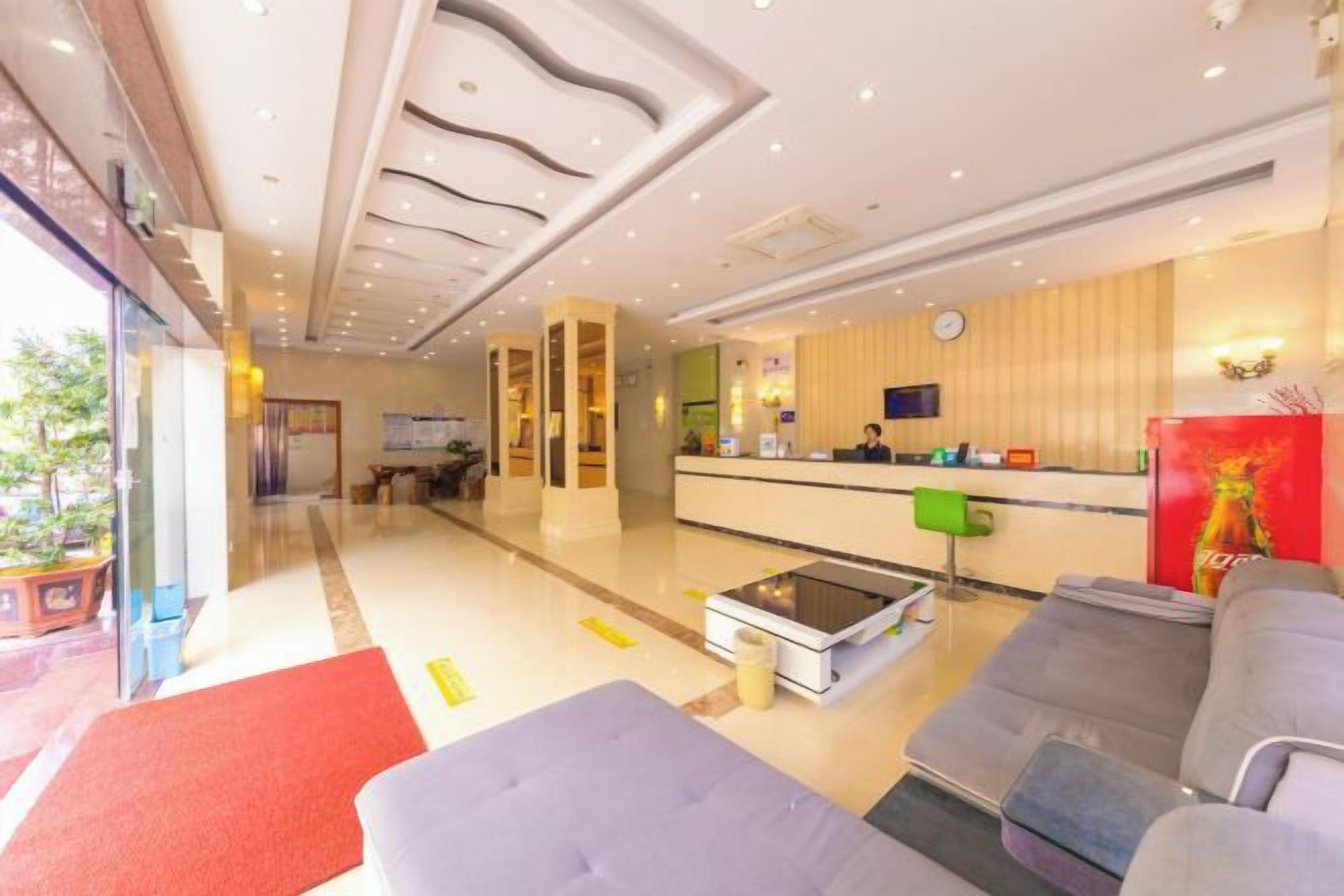 A hotel lobby with a reception desk, seating area, and a large window.