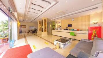 A hotel lobby with a reception desk, seating area, and a large window.