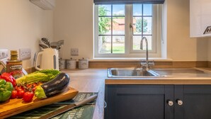 A kitchen with a wooden countertop, a sink, and a window with a view of the outside. - Jasmine Cottage, Sedgeford, Norfolk (Sedgeford)