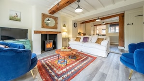 A living room with a fireplace, a television, and blue chairs. - Jasmine Cottage, Sedgeford, Norfolk (Sedgeford)