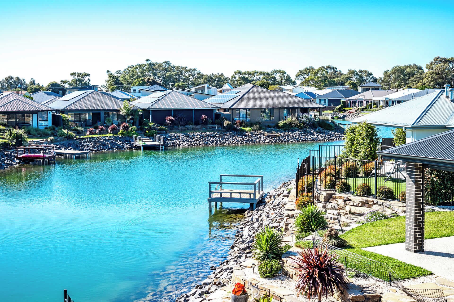 A residential area with a swimming pool, houses with similar architecture, and a dock.