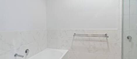 A bathroom with a bathtub, a glass shower enclosure, and a towel rack.