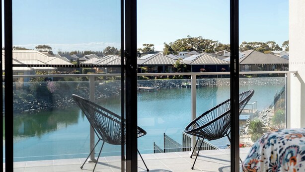 A balcony with a view of a pool and a marina, featuring modern black chairs and a clear sky. - 4-13 Central Dr Victor Harbor - Wi-Fi and Linen (Victor Harbor)