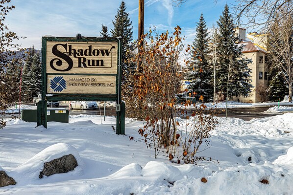 Cartell de Shadow Run gestionat per Mountain Resorts, Inc., envoltat de neu i arbres sense fulles.