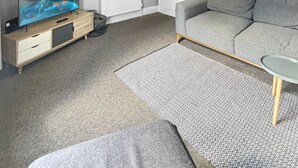 Una sala de estar moderna con un televisor de pantalla plana, un sofá gris y una alfombra estampada.