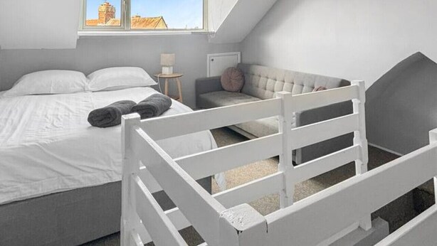 Un dormitorio con literas, una ventana con vistas, un ventilador de techo y una lámpara.