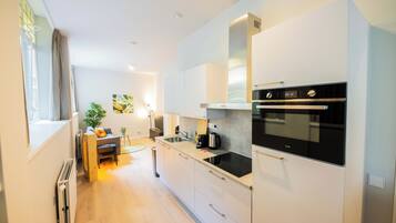 Een moderne keuken met witte kasten, een ingebouwde oven en een eethoek met een tafel en stoelen.