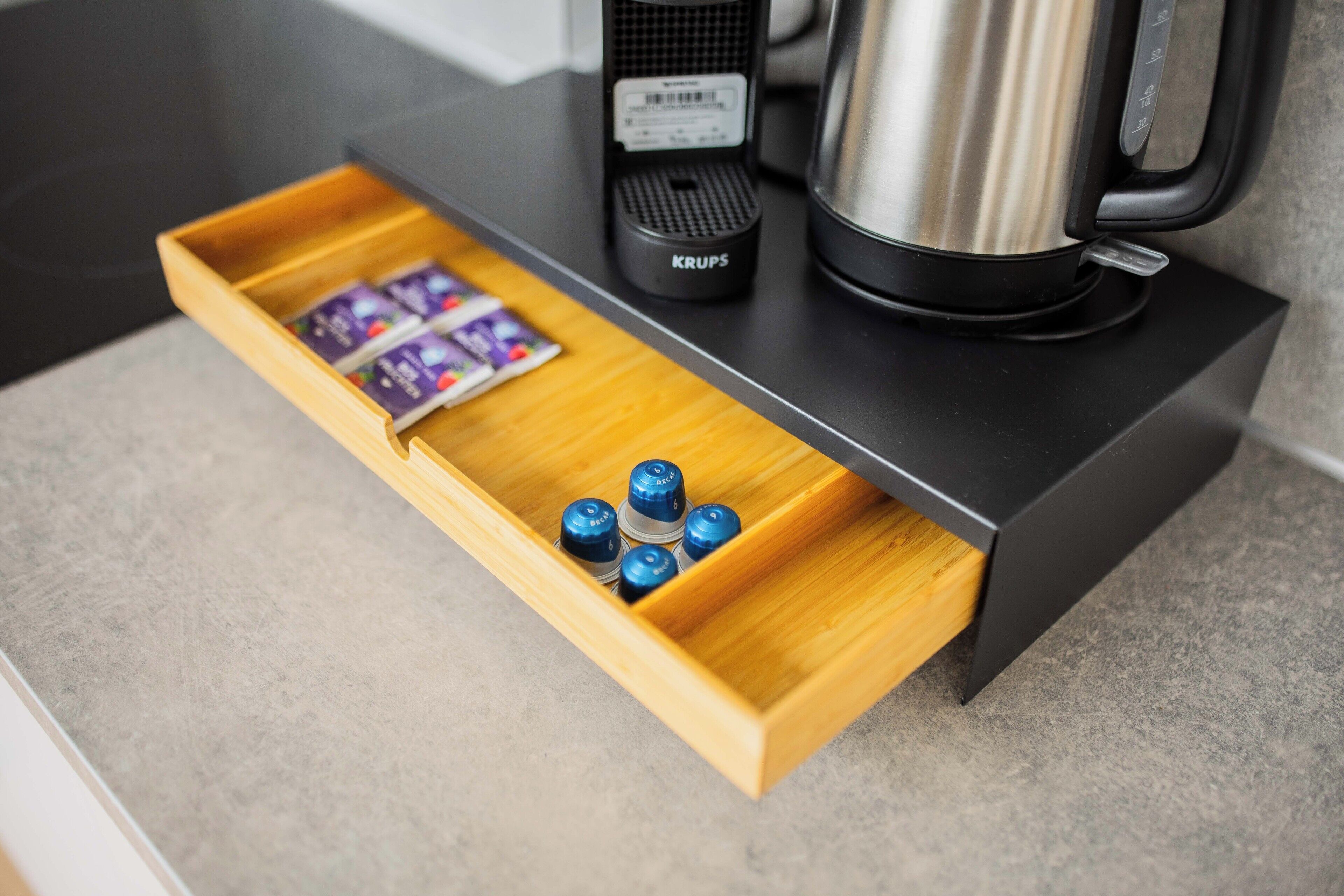 A wooden drawer with a coffee maker and Krups electric kettle on a countertop.