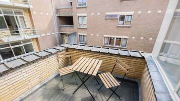 Terrassa al terrat amb taules i cadires de fusta, parets de maó i diverses finestres.