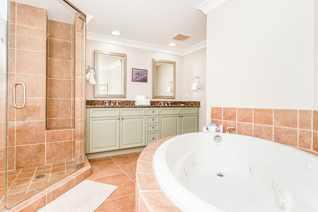 Une salle de bain avec une grande baignoire, un espace douche et des meubles de couleur vert clair.