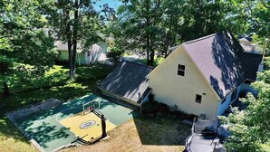 A house with a basketball court, a trampoline, and a pond. - Family-Friendly Lakeside Getaway in the Heart of Traverse City! (Traverse City)