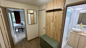 A bathroom with a wooden vanity, a mirror, and a sink with a glass shelf.
