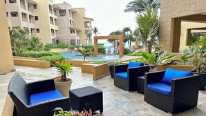 Une terrasse d’hôtel avec des sièges en plein air, une piscine et une végétation luxuriante.