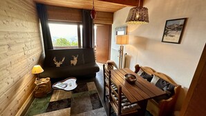 A cozy room with a wooden sofa, a dining table, and a lamp.