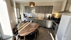 Eine moderne Küche mit grauen Schränken, einem Holztisch und einem eingebauten Backofen.