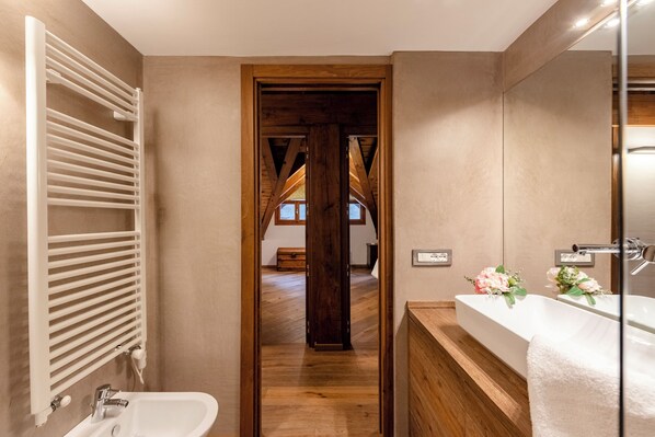 A modern bathroom with a wooden floor, a white sink, and a large mirror. - Appartamento 3 Camere Letto Courmayeur (Courmayeur)