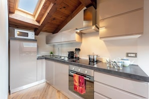 Una cucina moderna con finestra sul tetto, elettrodomestici in acciaio inossidabile e soffitto in legno.