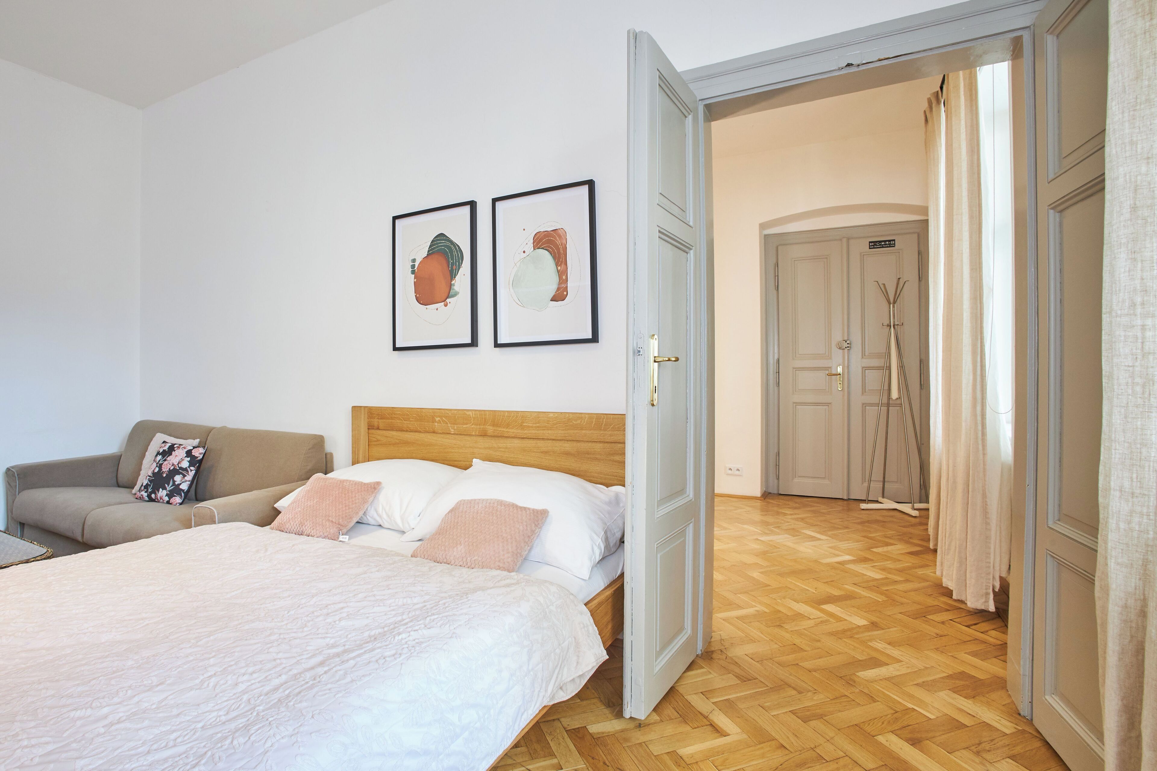 Un dormitorio con una cama, un sofá y dos cuadros en la pared.