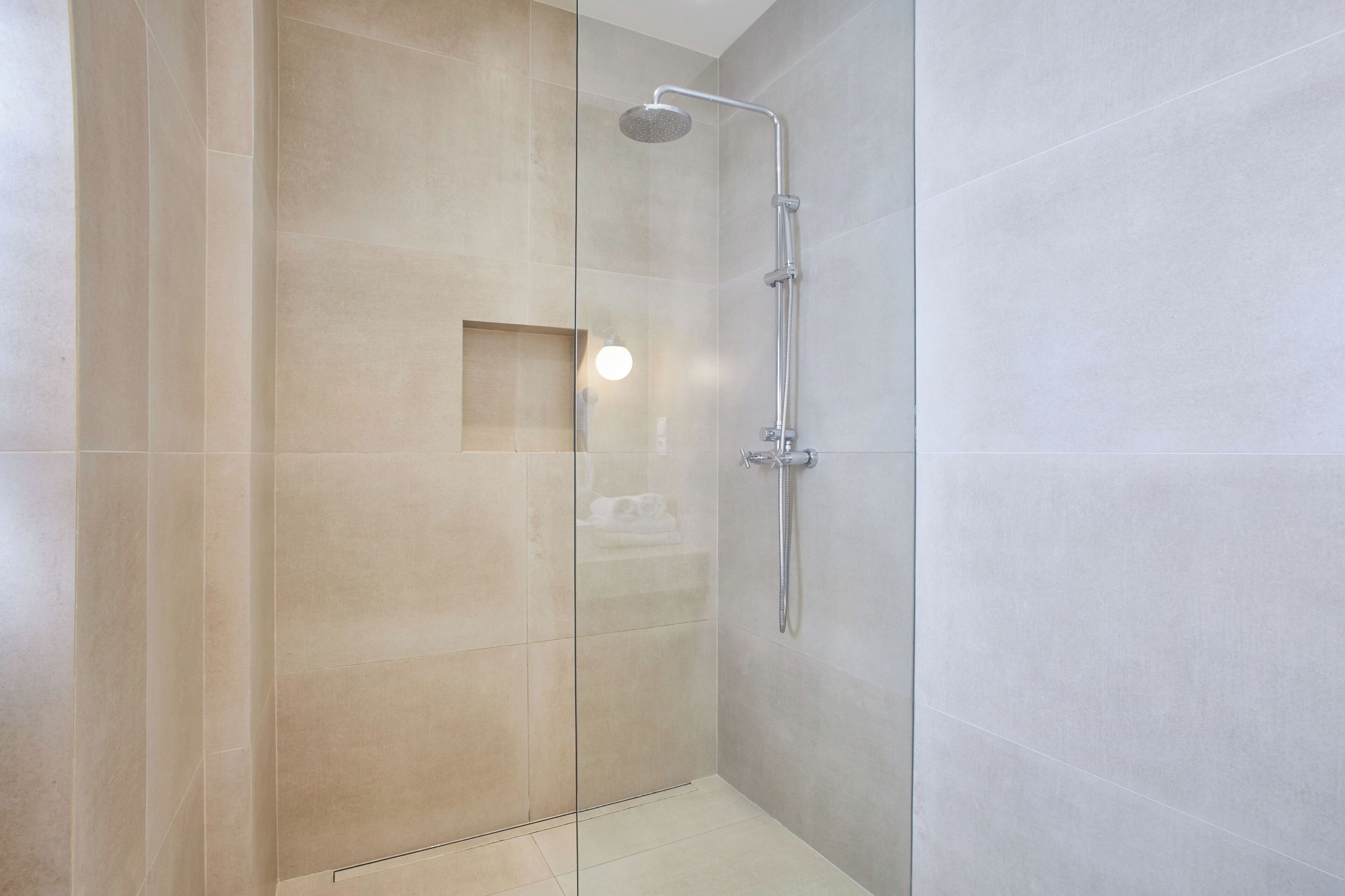 A modern shower with a glass door and a handheld showerhead.