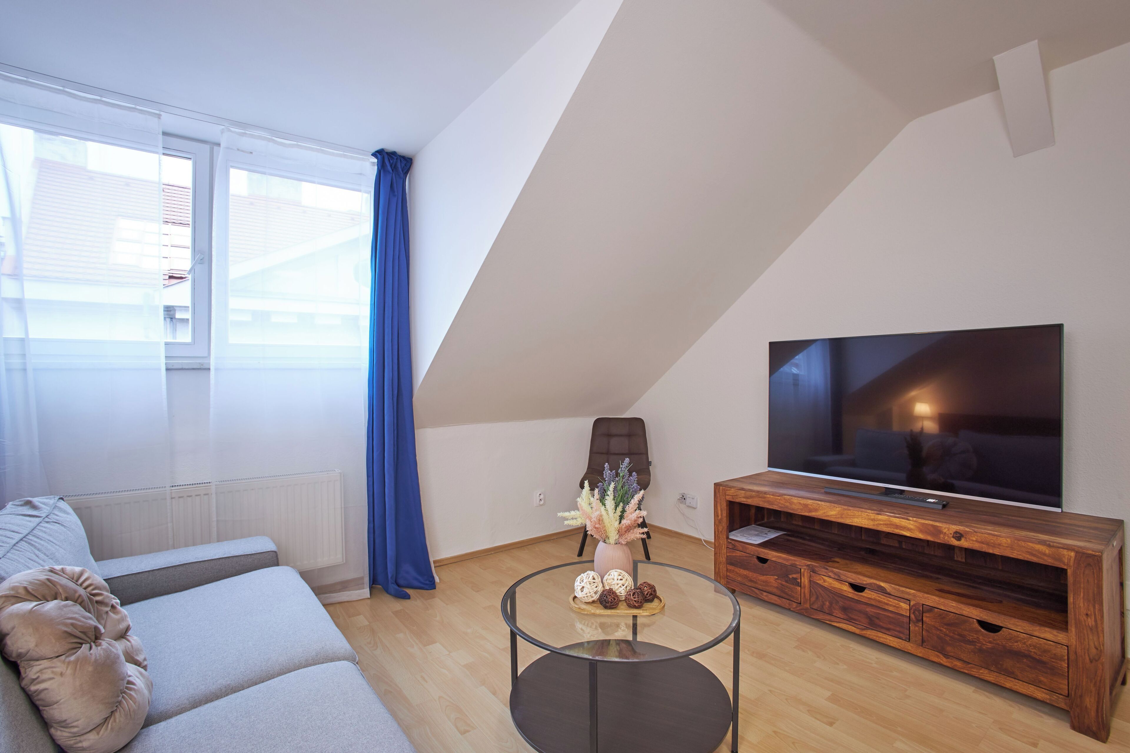 Un salon moderne avec un canapé, une table basse en verre, un meuble TV en bois et un grand téléviseur à écran plat.