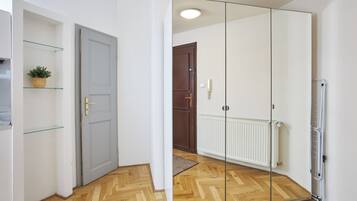 Una habitación con armario espejado, suelo de madera, radiador y puerta con picaporte.