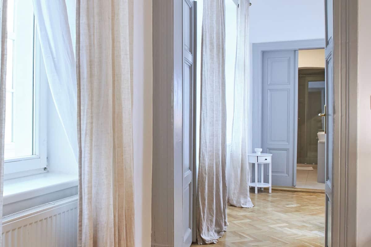 A hallway with wooden flooring, white walls, and a door leading to a bathroom.