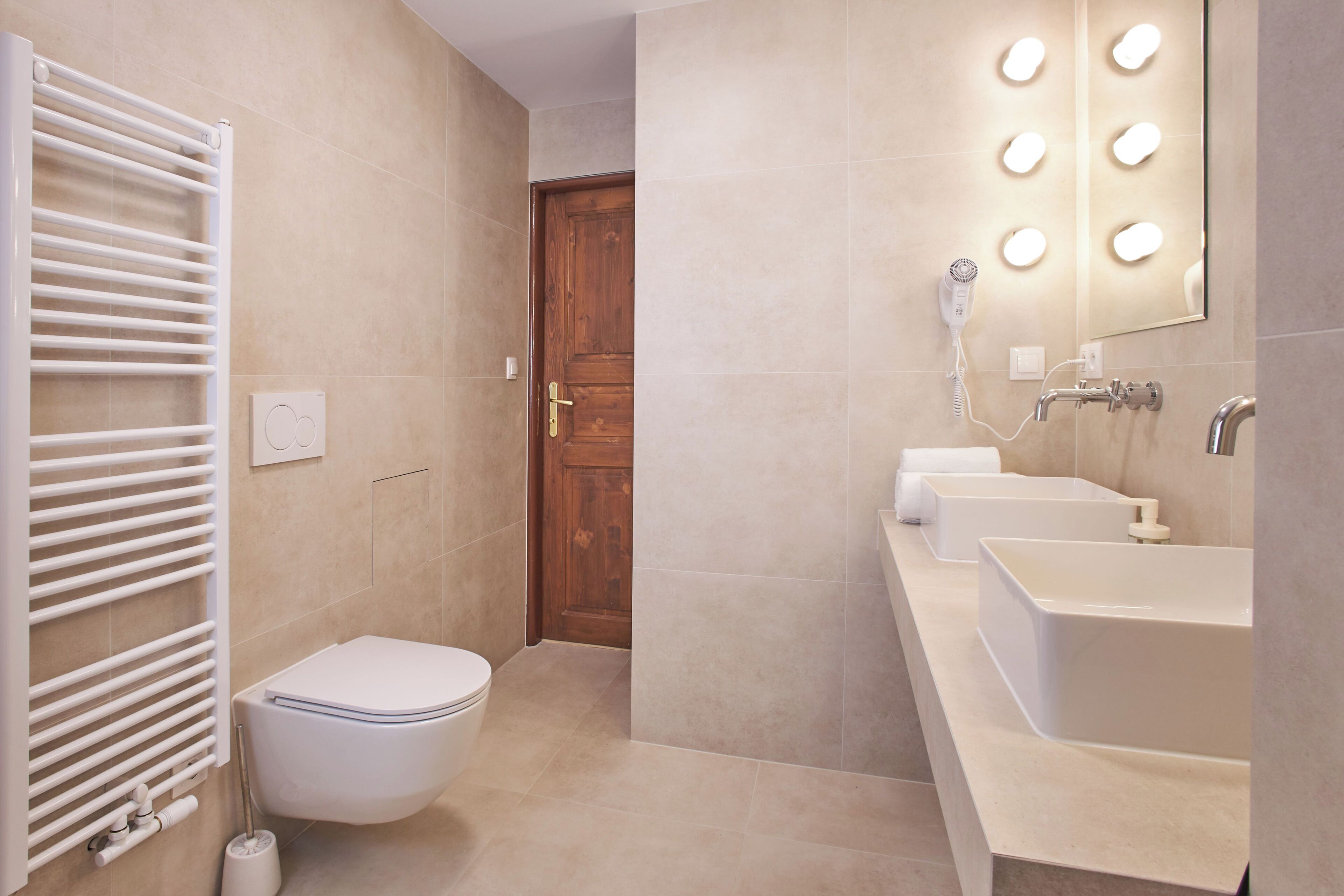 A modern bathroom with a white toilet, a towel rack, a hairdryer, and a vanity with a mirror.