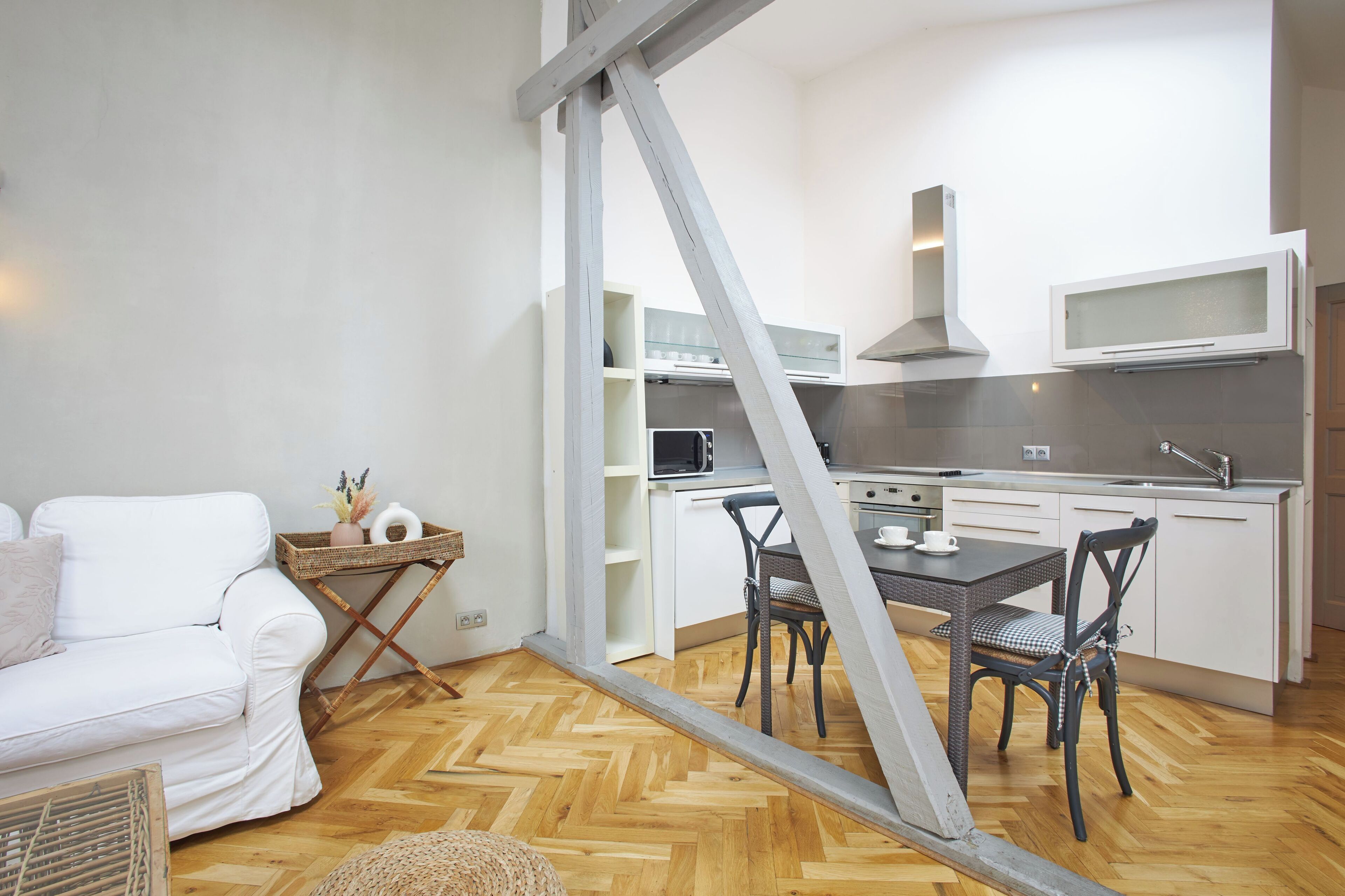 A compact living space with a kitchenette, a dining area with a table and chairs, and a white sofa.
