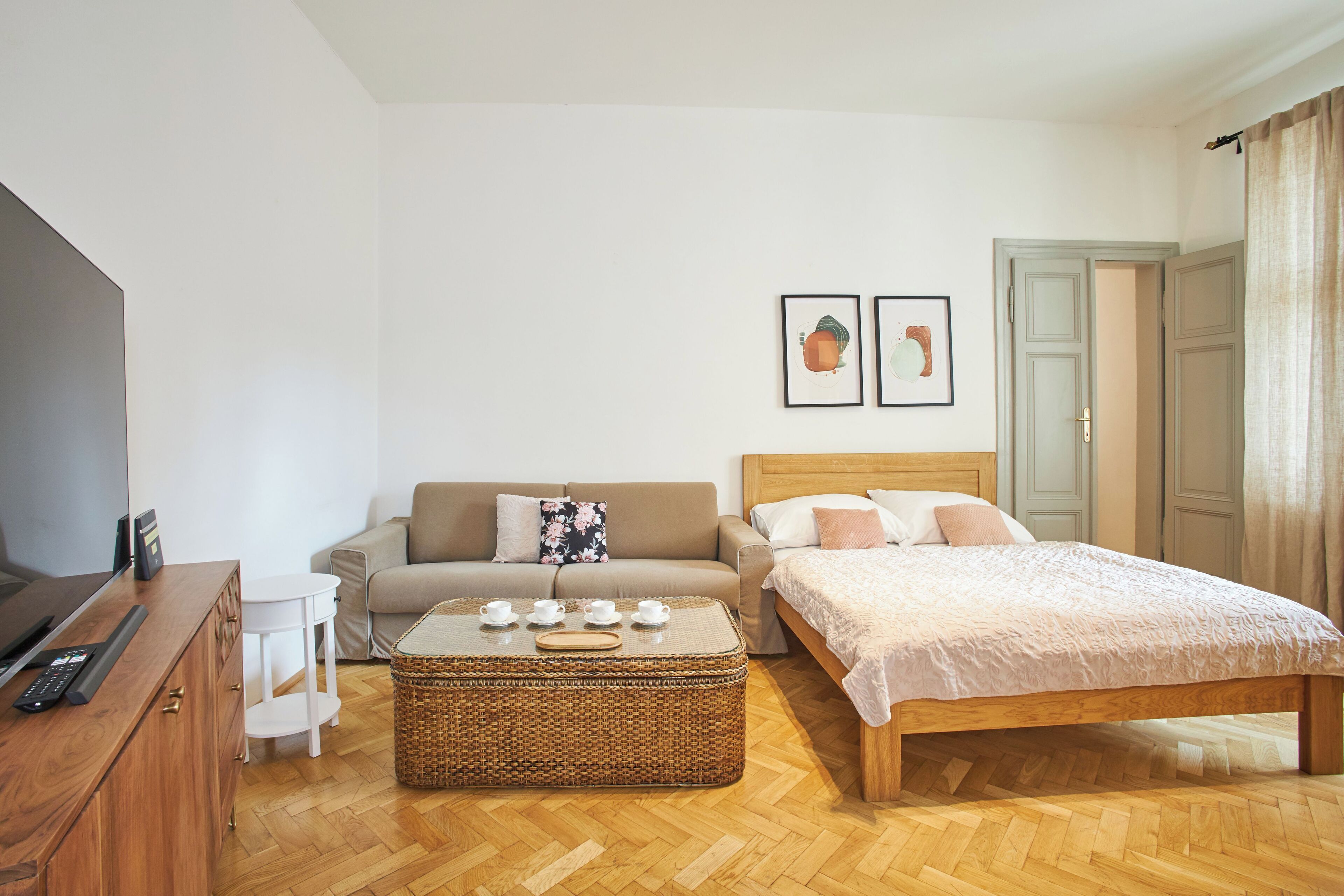 Une chambre à coucher avec un lit en bois, un canapé, une télévision et une petite table avec des tasses.