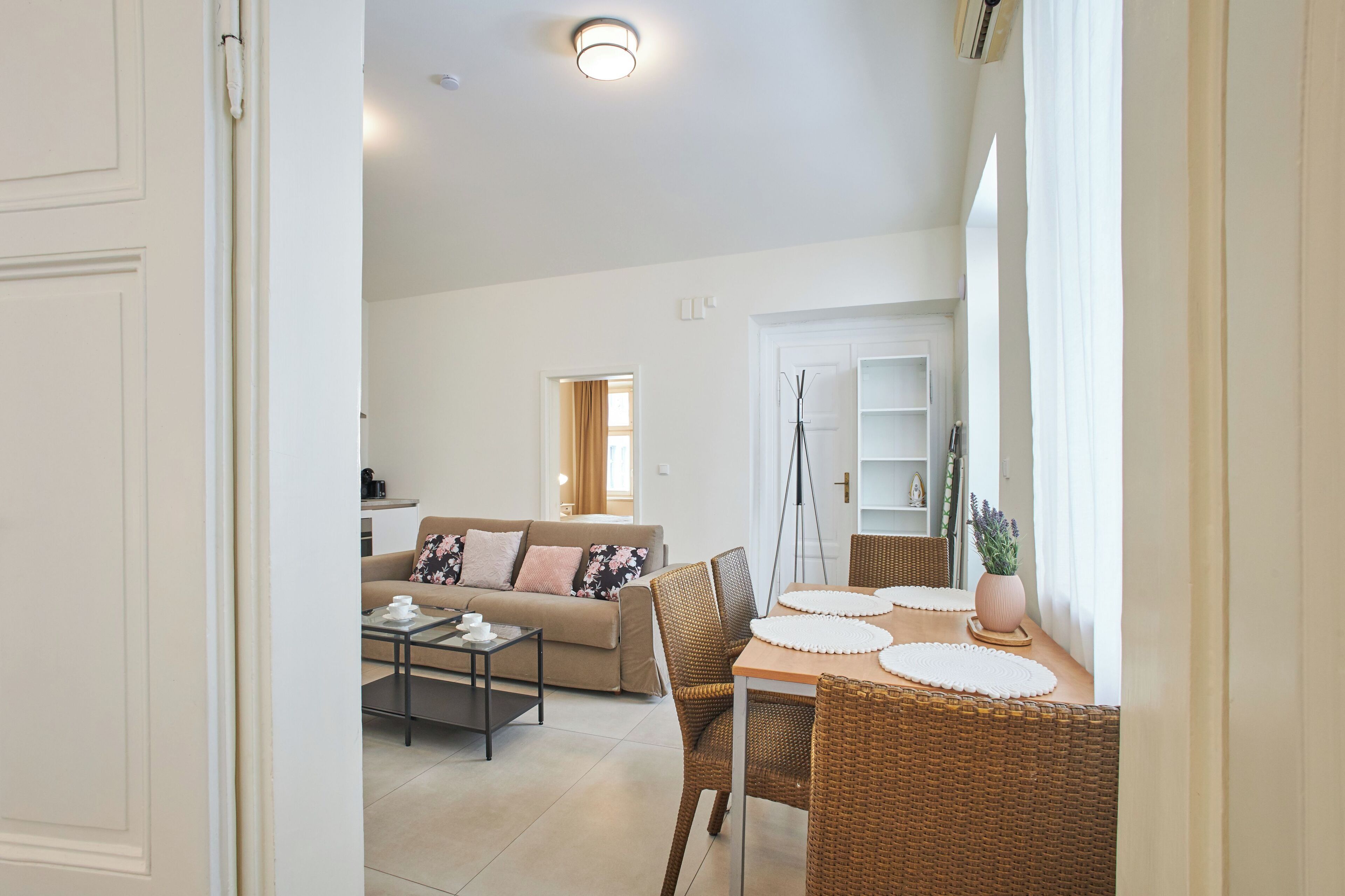 A modern living room with a sofa, coffee table, and dining area with wicker chairs and a table.