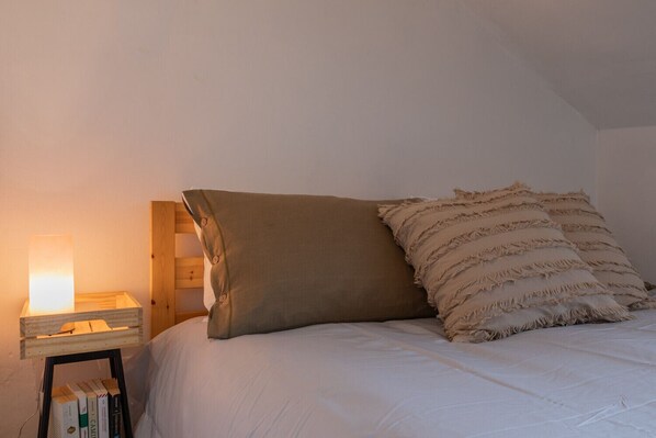 A bedroom with a bed, a nightstand with a lamp, and a wooden headboard.