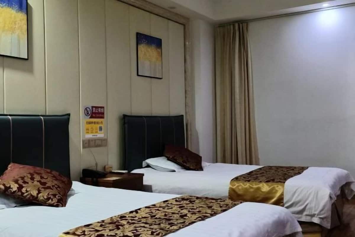 A hotel room with two beds, a nightstand, a painting on the wall, and a window with curtains.