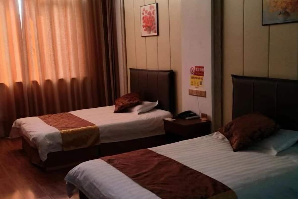 A hotel room with two beds, a nightstand, a telephone, and a wall-mounted sign.