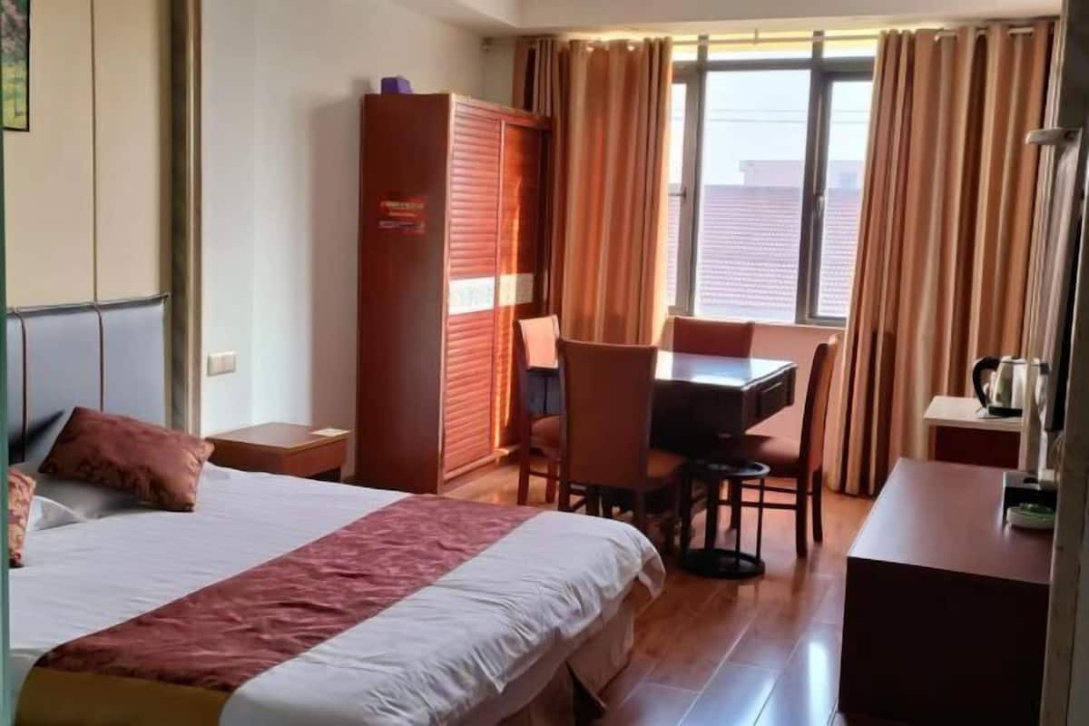 A hotel room with a bed, a desk, a chair, and a wardrobe.