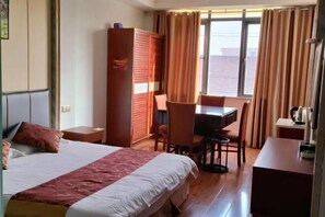 Habitación de hotel con cama, escritorio, silla y armario.